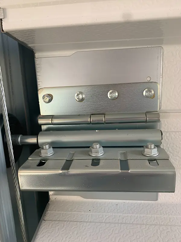 Heavy-duty galvanized steel side hinge and roller bracket installed on the sectional garage door panel.