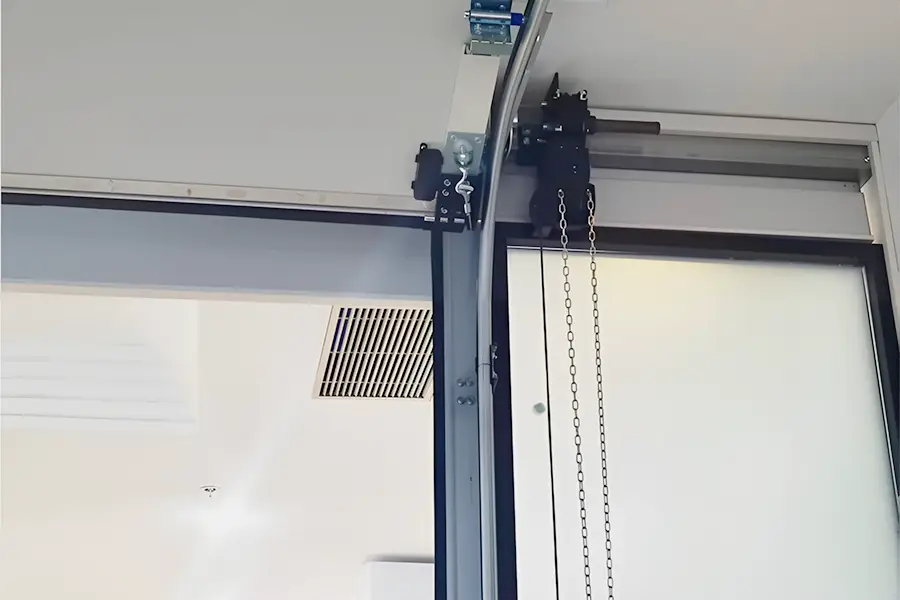 Installation of industrial sectional door showing heavy-duty tracks, motor, and manual hoist chain.